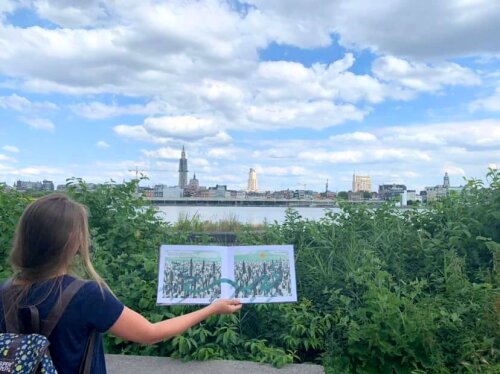 Picture book held before a view on Antwerp